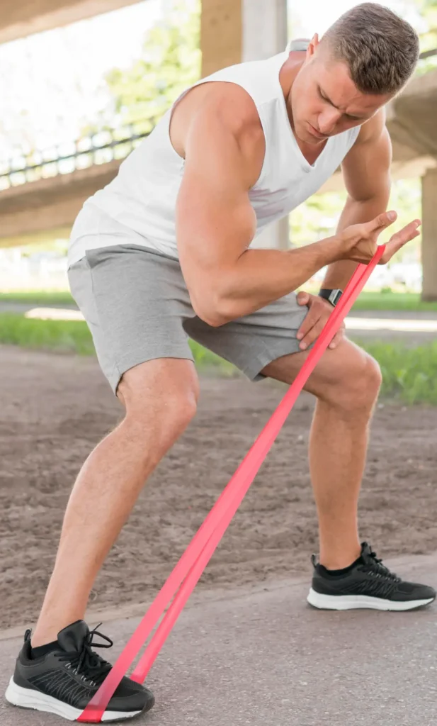 un homme qui fait du curl biceps avec un élastique en extérieur